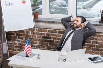 Wall Mural - successful businessman with hands on head sitting in modern office