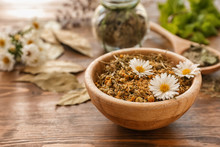 Bowl With Dried Chamomile Flowers On Wooden Table