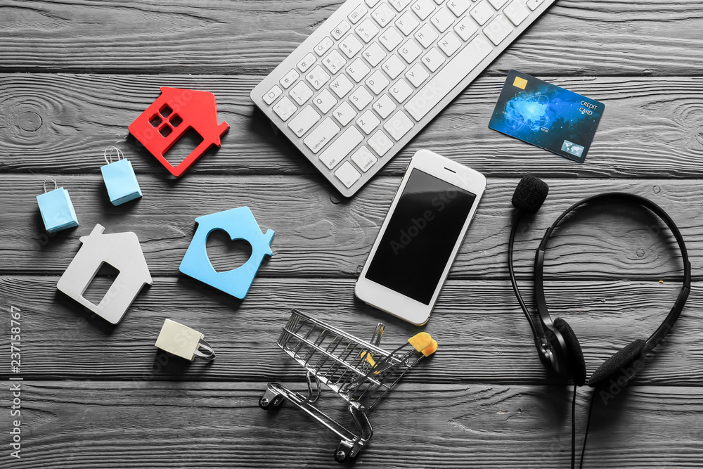 Composition with small cart, computer keyboard and mobile phone on wooden background. Online shopping