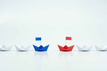 Blue and red paper ship leading among white. leaders of two business teams or competition of two leaders concept.