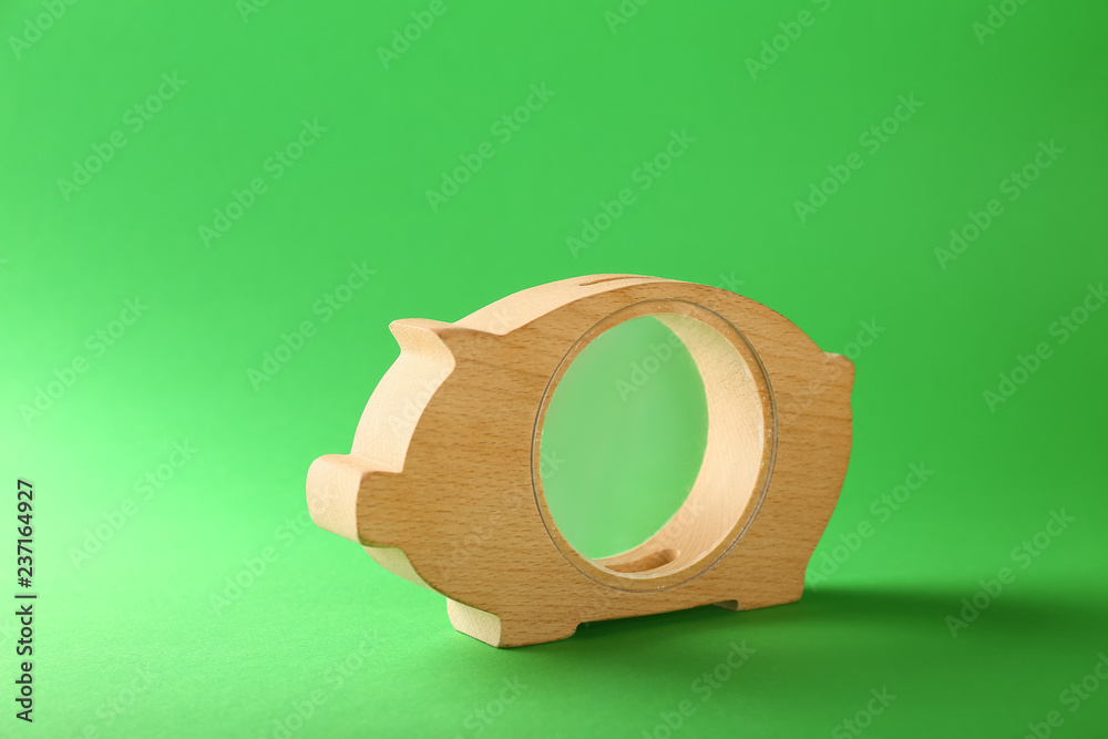 Wooden piggy bank on color background