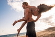 Nice couple of young people enjoy the beach and vacation time in summer together playing - friendship and relationship love concept for people have fun outdoor - man carry girl on his back