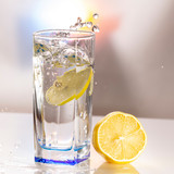 Fototapeta Kuchnia - A glass of lemonade on a light background with splashing water
