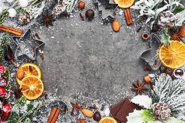 Holiday baking background for baking Christmas cookies with cutters and spices on grey concrete table. Holiday baking or cooking ingredients. Christmas food. Top view with copy space for text.