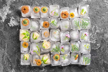 Beautiful Flowers Frozen In Ice Cubes On Grey Background, Top View