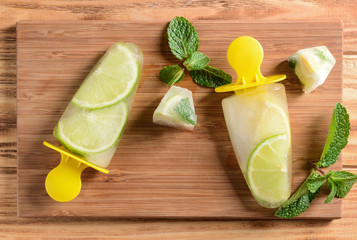 Popsicles with cutting board on wooden background