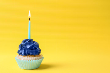 Tasty cupcake with burning candle on color background