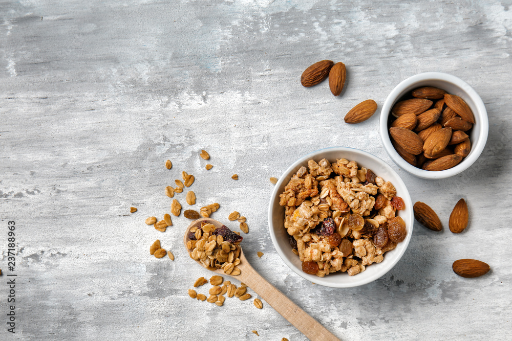 Granola with raisins and almonds in bowls on grey background