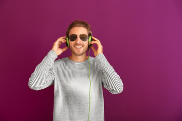 Poster - Young man listening to music on color background