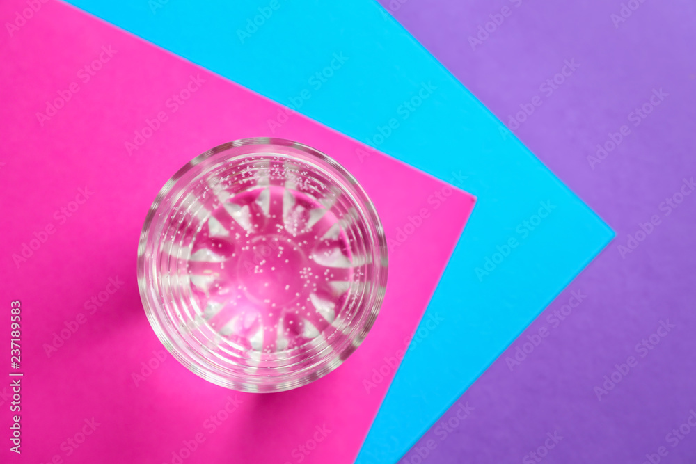 Glass of fresh water on color table