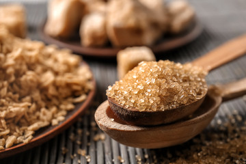Wall Mural - Wooden spoons with brown sugar on table, closeup