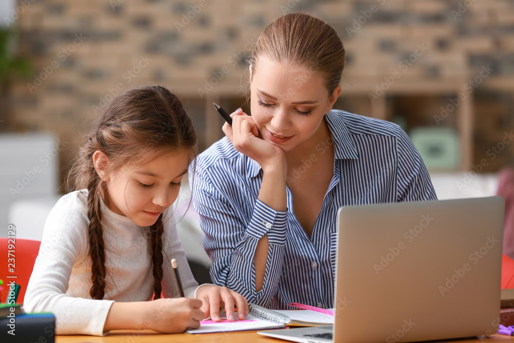 Cute girl with mother doing homework at home