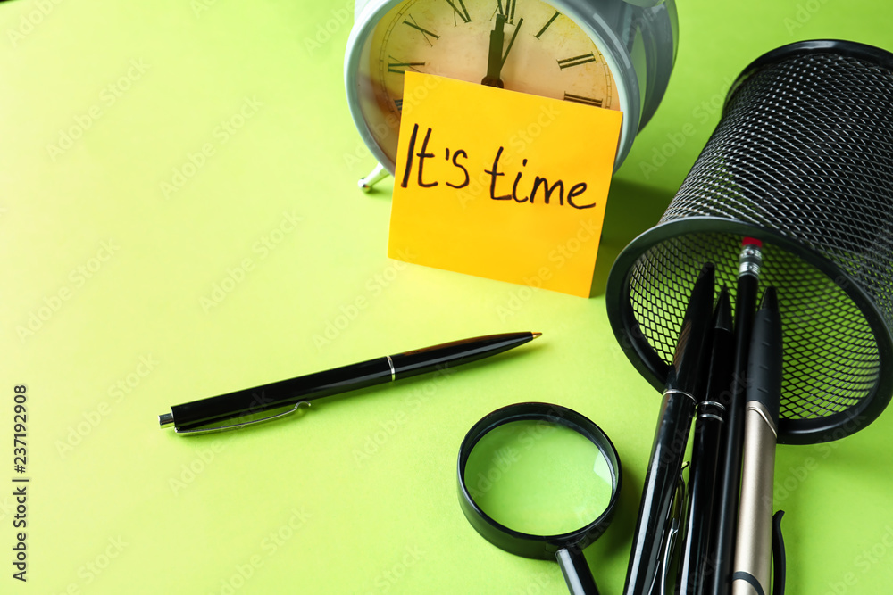 Paper sheet with text IT'S TIME, stationery and alarm clock on color table. Deadline concept