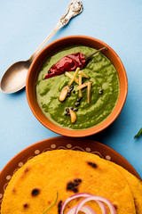 Makki di roti with sarson ka saag, popular punjabi main course recipe in winters made using corn breads mustard leaves curry. served over moody background. selective focus