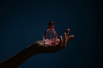 Wall Mural - Woman holding bottle of perfume on dark color background