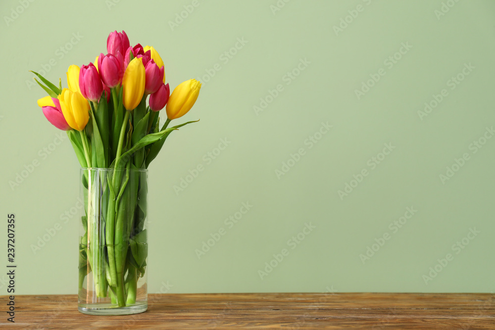 Vase with beautiful tulips on wooden table