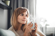 © leszekglasner - Happy woman in soft sweater relaxing at home with cup of hot tea or coffee