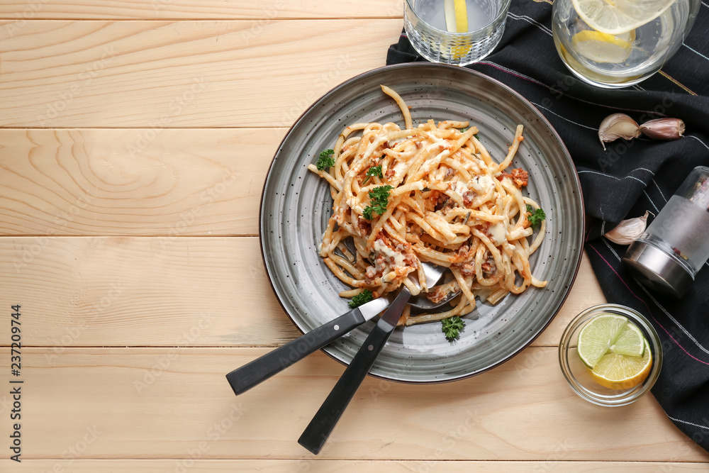 Plate with delicious pasta bolognese on wooden table, top view