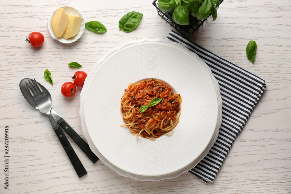 Plate with delicious pasta bolognese on white wooden table, top view