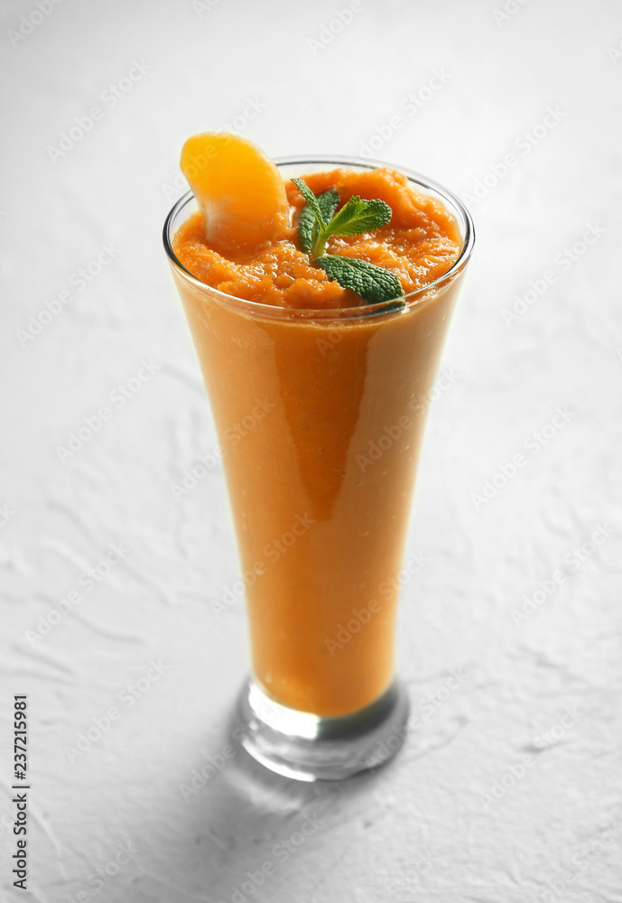 Glass of tasty orange smoothie on white table