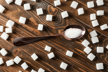 Spoon with sugar and cubes on wooden table