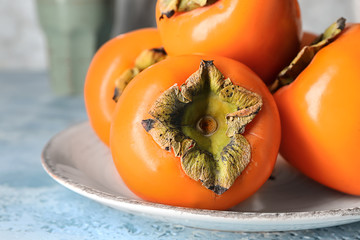 Plate with ripe persimmons on table, closeup