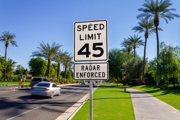 Wall Mural - Speed Limit 45 Radar Enforced road sign with passing cars on a California street.