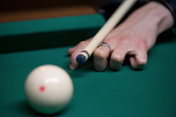 Wall Mural - Sport billiard balls on green billiard table in pub. Player is about to hit the ball, focusing on his shot. On going billiard game. Competitive players trying to find out the winner of the round.  