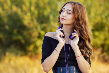 Wall Mural - portrait of a music lover teenager girl in headphones, young woman listening to lovely song on the nature in the field