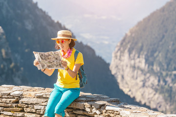 Wall Mural - Happy woman traveler with a backpack and a map on the background of the Pyrenees mountains. Hiking and adventure concept