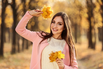 Wall Mural - Beautiful woman with maple leafs in autumn park