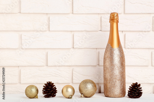 Fotografía Champagne bottle with christmas baubles and cones on brick wall background