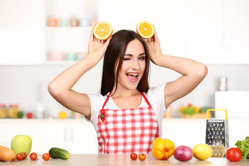 Wall Mural - Beautiful woman holding sliced orange fruit and cooking food in the kitchen