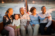 © Erickson Stock - Mature adult couple sitting with a mid-adult couple and their young daughter on a boat at sunset.