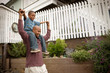 © Erickson Stock - Father carrying his young son on his shoulders down a suburban street.