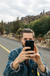 © Jesse Morrow/Stocksy - Young male taking photo with phone using electronics in outdoor nature scene