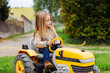© BONNINSTUDIO/Stocksy - Blonde little girl driving a tractor in a farm.