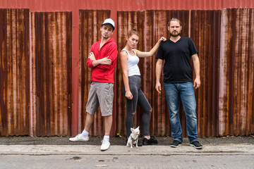 Group of friends standing against old rusty sheet wall with woma