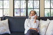 © Trinette Reed/Stocksy - Mature woman with grey hair talking on landline phone in living room