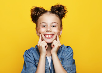 portrait of cheerful smiling little girl on yellow background