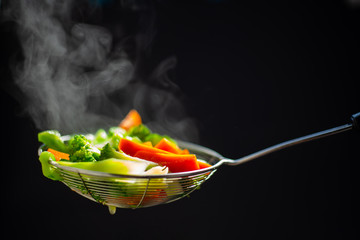 The steam from the vegetable colander in the dark