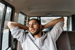 © Jesse Morrow/Stocksy - Young adult male relaxing in back of car while on road trip