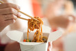 © Pixel-Shot - Woman eating chinese noodles from takeaway box, closeup