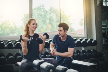 Beautiful woman is exercising and fitness. The trainer gives instructions on how to exercise in the gym.