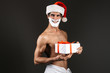© Drobot Dean - Young santa naked man posing isolated over dark wall background holding gift box dressed in towel with shaving gel on beard.