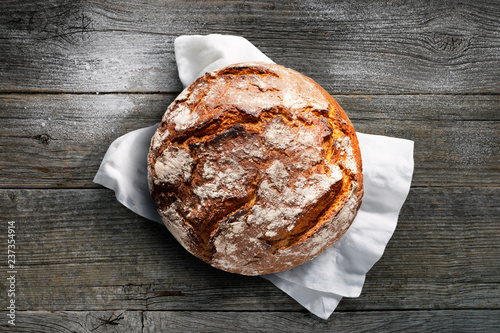 Cuadros en Lienzo Rustikales Brot auf weißem Tuch mit dunklem Holzuntergrund