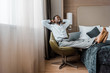 © LIGHTFIELD STUDIOS - smiling young african american businessman relaxing in hotel room with laptop