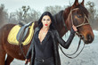 Beautiful woman in a black suit near a horse.