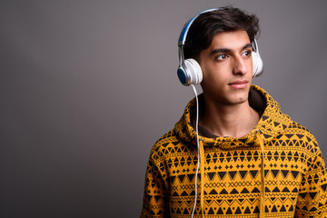 Wall Mural - Young handsome Persian teenage boy thinking against gray background