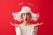 © Drobot Dean - Excited young shocked woman dressed in carnival christmas costume posing isolated over red wall background.